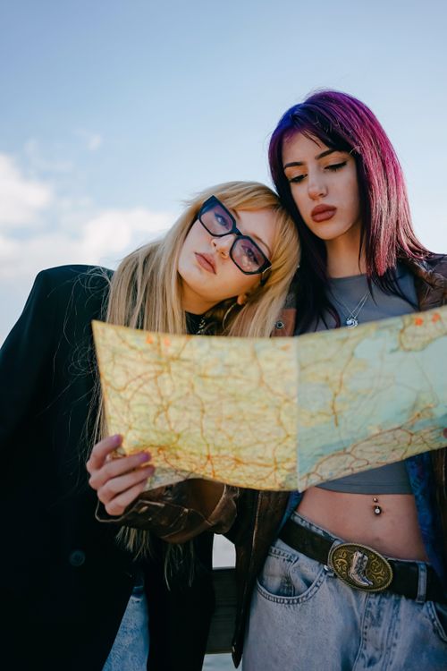 Free Two young women studying a map outdoors, symbolizing adventure and travel exploration. Stock Photo