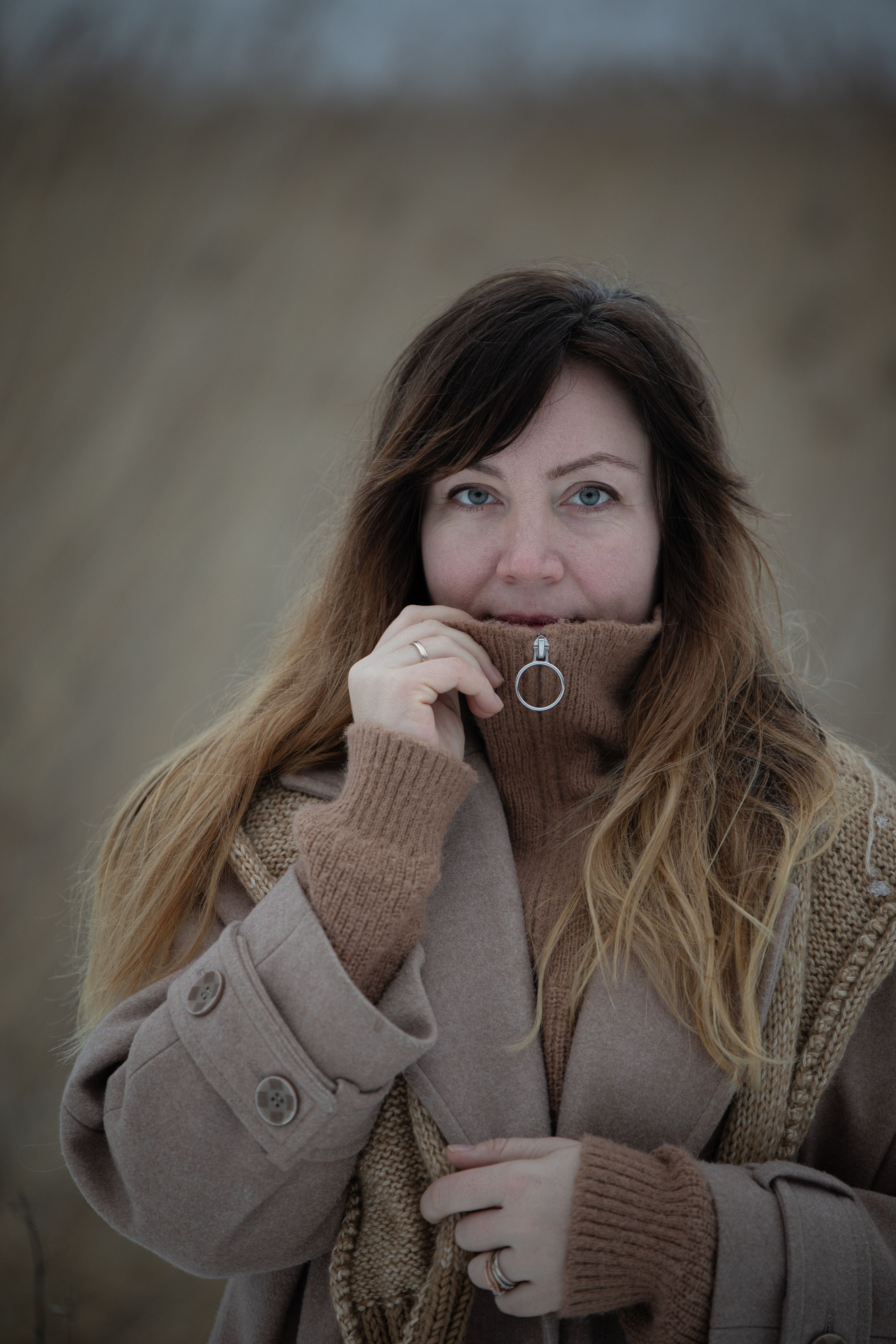 A woman in a brown winter coat outdoors, showcasing a cozy winter style.