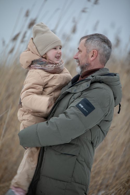 Free Father and child in warm jackets sharing a moment in a winter field. Stock Photo