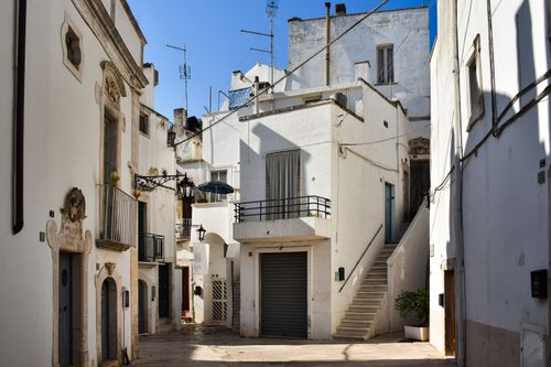 Free Explore the picturesque whitewashed architecture of a historic street in Puglia, Italy under clear skies. Stock Photo