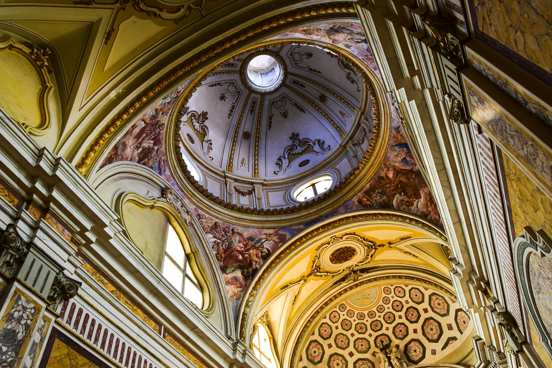 Intricate dome interior with frescoes and ornate design in Italian architecture, showcasing Renaissance art.