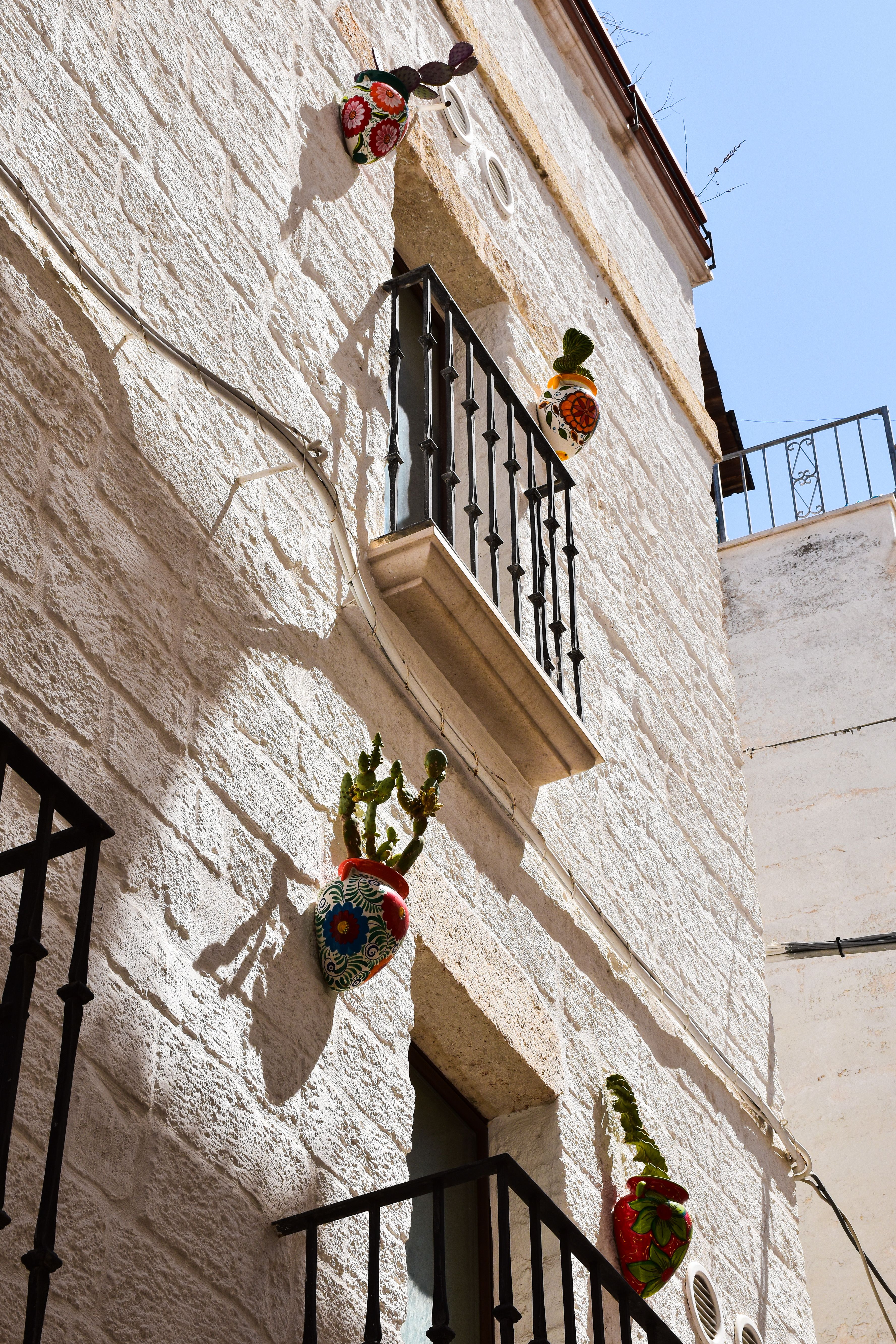 A Mediterranean building with decorative pots on a stone facade under a clear blue sky.