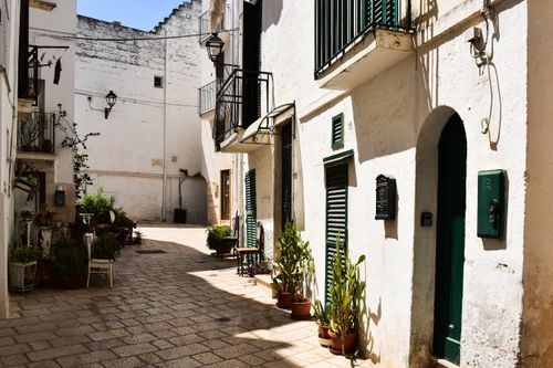 Free Sunlit alleyway in a classic Puglian town with whitewashed buildings and plants. Stock Photo