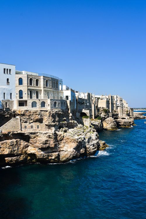 Free Scenic view of historic architecture perched on cliffs along the Adriatic Sea in Polignano a Mare, Italy. Stock Photo