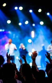 Vibrant concert scene with enthusiastic crowd enjoying live music under colorful stage lights.