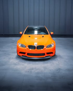 Front view of an orange sports car in a modern indoor setting, showcasing sleek design.