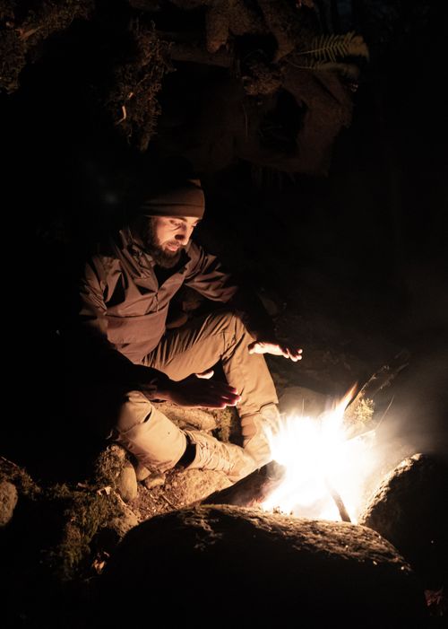Free A man warms his hands by a campfire during a night in the forest. Stock Photo