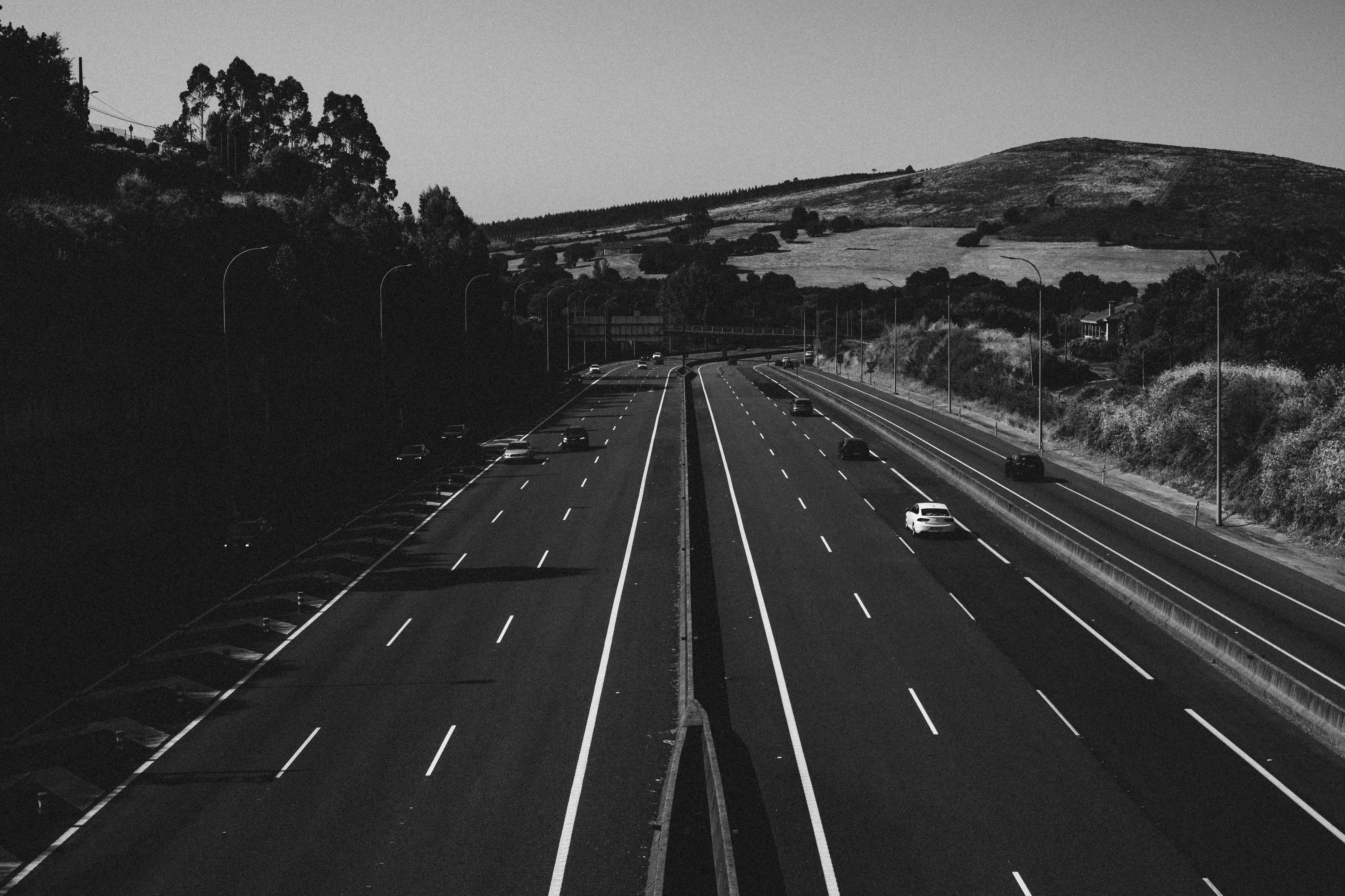 Black and white photo of a highway in Santiago di Compostela, Spain, surrounded by scenic hills.