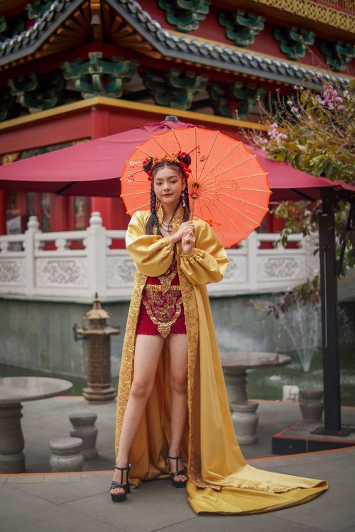 Free A woman in traditional attire holds a vibrant parasol in a cultural setting. Stock Photo
