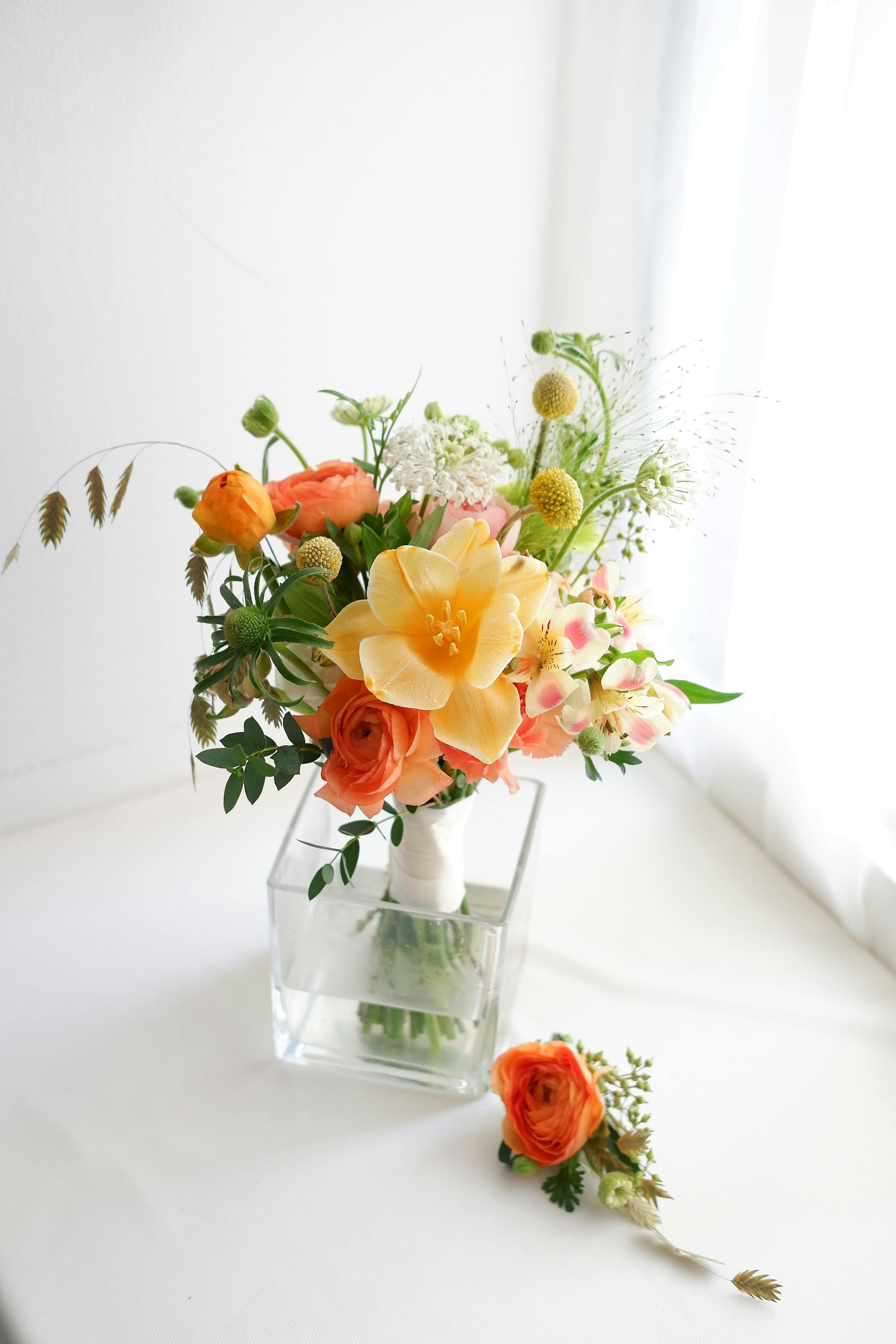 Elegant bouquet of orange and yellow flowers in a clear glass vase perfect for home decor.