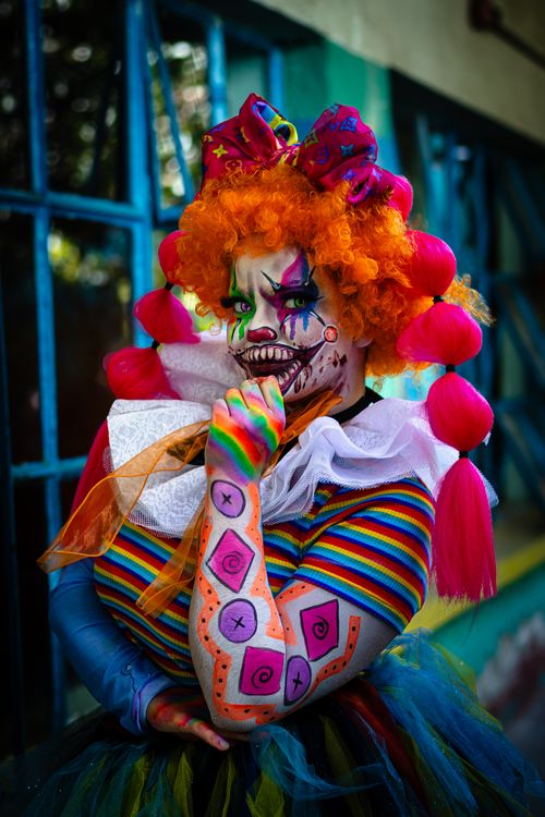 Free Colorful horror clown in vibrant makeup poses outdoors in Mexico City. Stock Photo