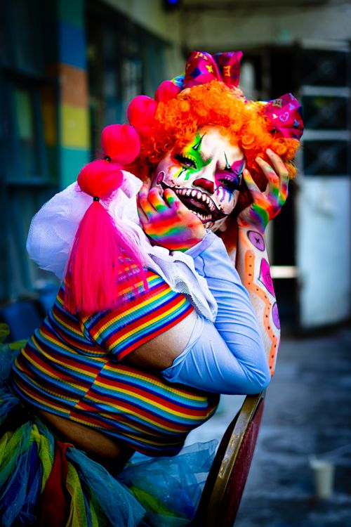 Free Colorful clown makeup and attire in a lively street setting, perfect for horror or cosplay themes. Stock Photo