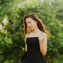 一位穿着休闲装的美女在绿树成荫的户外优雅地微笑着