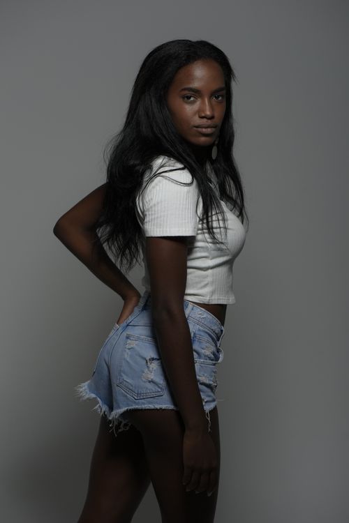 Free Young woman in casual outfit posing confidently against a neutral backdrop. Stock Photo