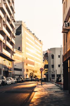 A quiet urban street illuminated by the golden light of sunrise, showcasing modern architecture.