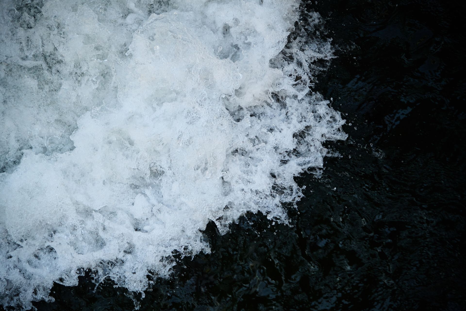 An artistic capture of a turbulent water flow with frothy white and deep black contrasts.