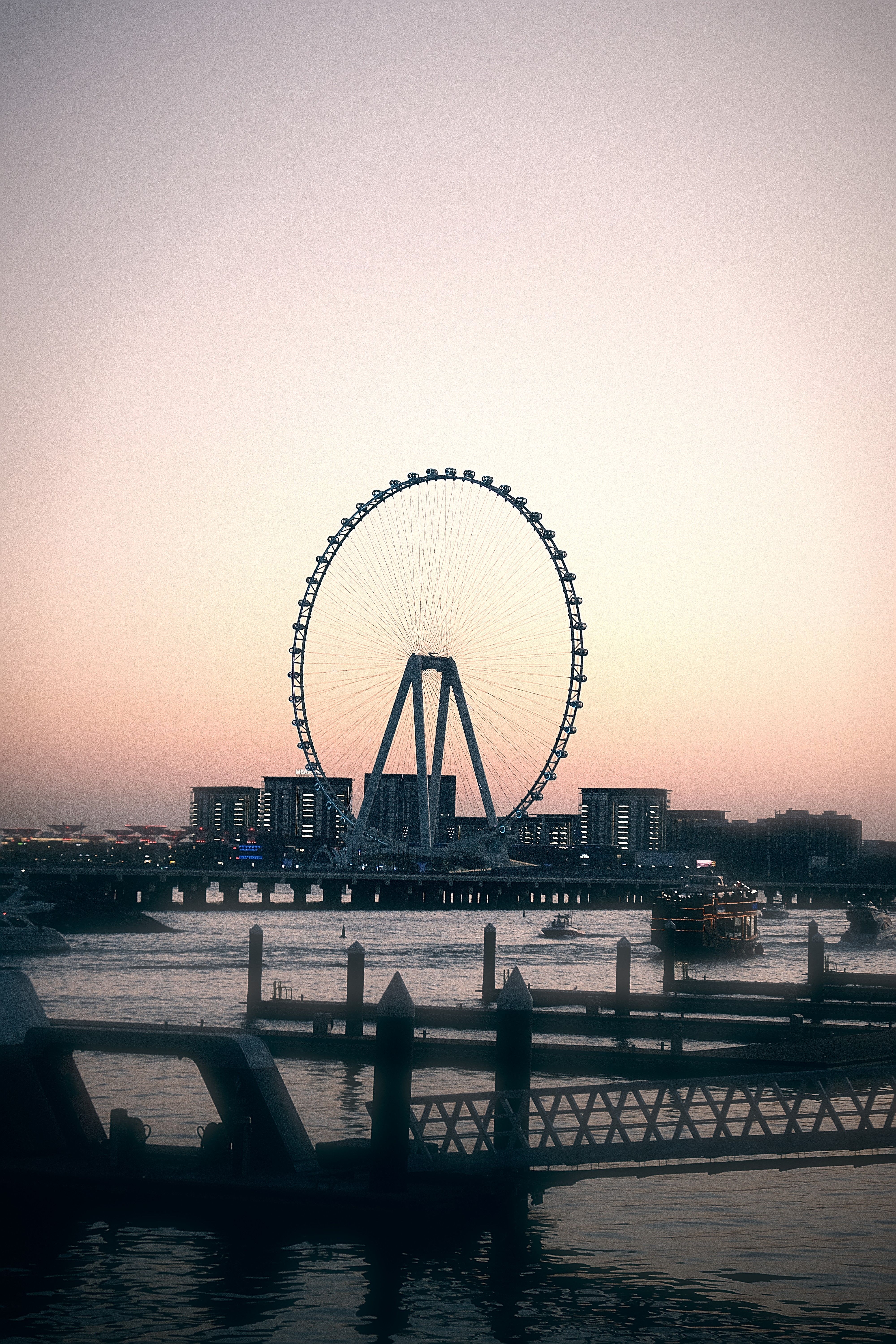 A serene view of Ain Dubai Ferris Wheel with sunset glow over calm waters.