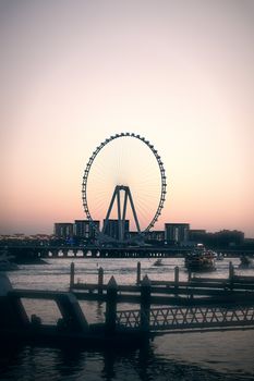A serene view of Ain Dubai Ferris Wheel with sunset glow over calm waters.