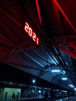 A striking night shot of Konnagar railway platform with a bright digital clock displaying 20:21.