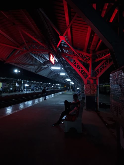Free A dimly lit Indian railway station platform at night with a lone figure seated. Stock Photo