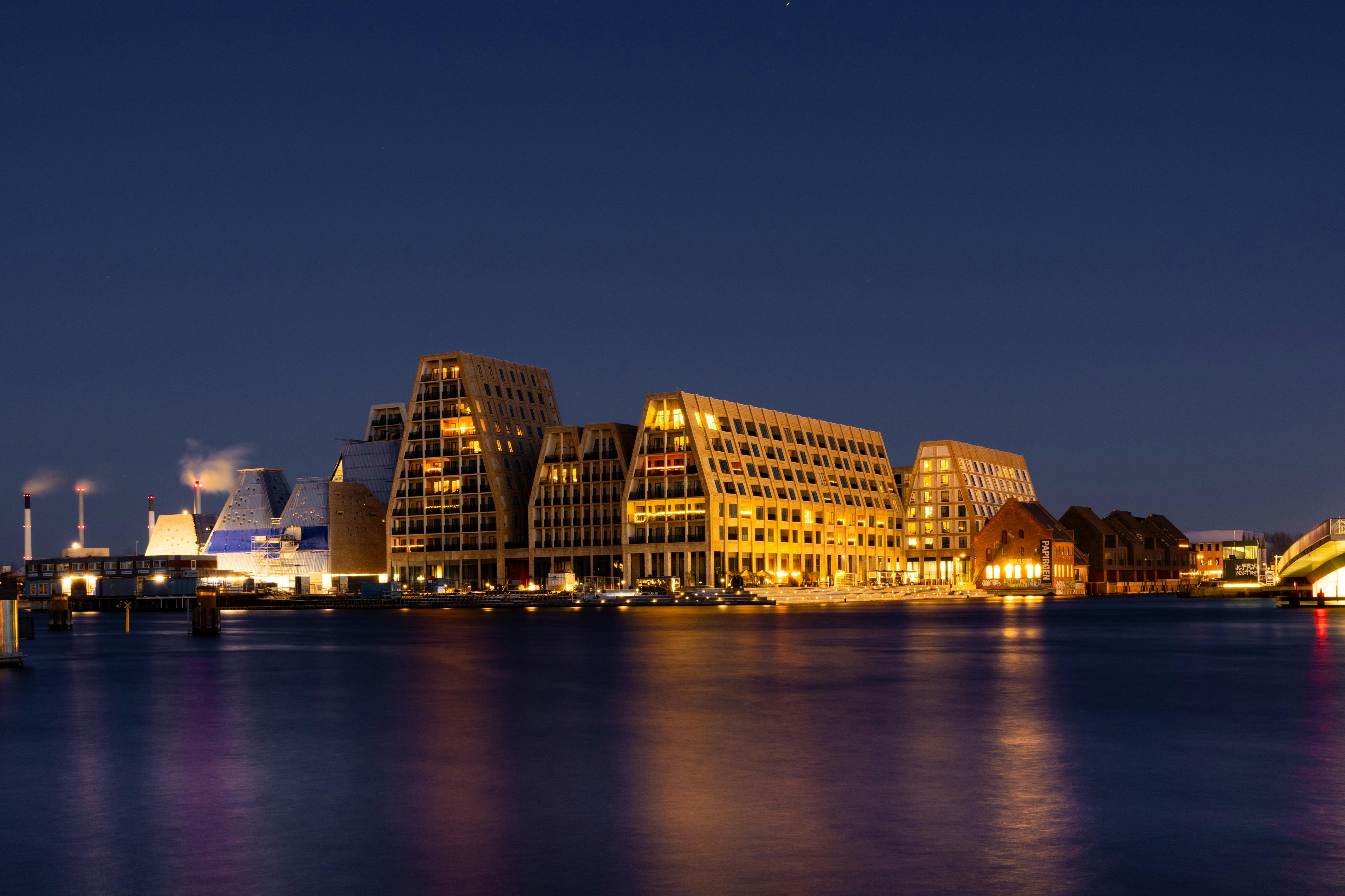 Night view of illuminated modern buildings by the water in Copenhagen.