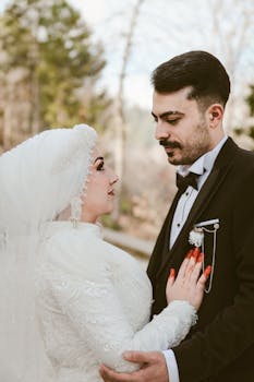 A couple in elegant attire celebrates their wedding outdoors among nature.