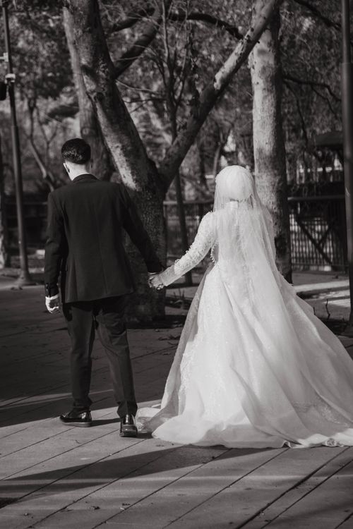 Free Elegant black and white photo of a couple in wedding attire strolling outdoors. Stock Photo