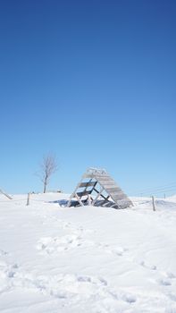 A snowy landscape in Mavrovo with a clear blue sky and a wooden structure.
