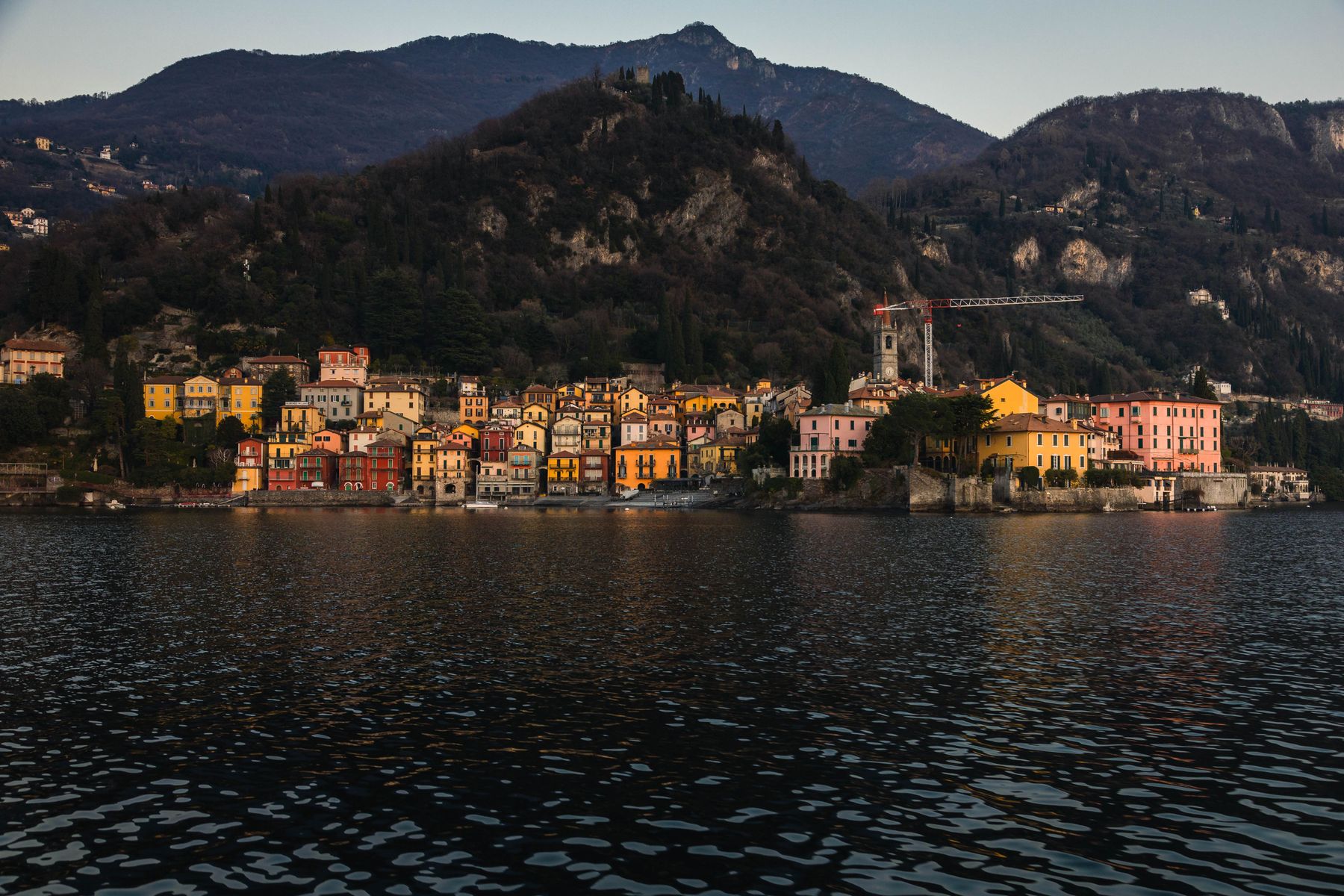 A lakeside town of pastel houses at dusk beneath steep mountains — photo by Sabine Meier on Pexels
