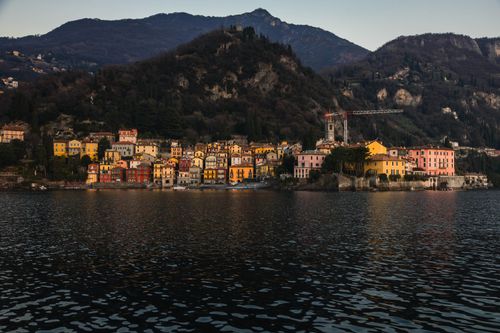 Free Charming Italian town on Lake Como with colorful houses at dusk, surrounded by mountains. Stock Photo