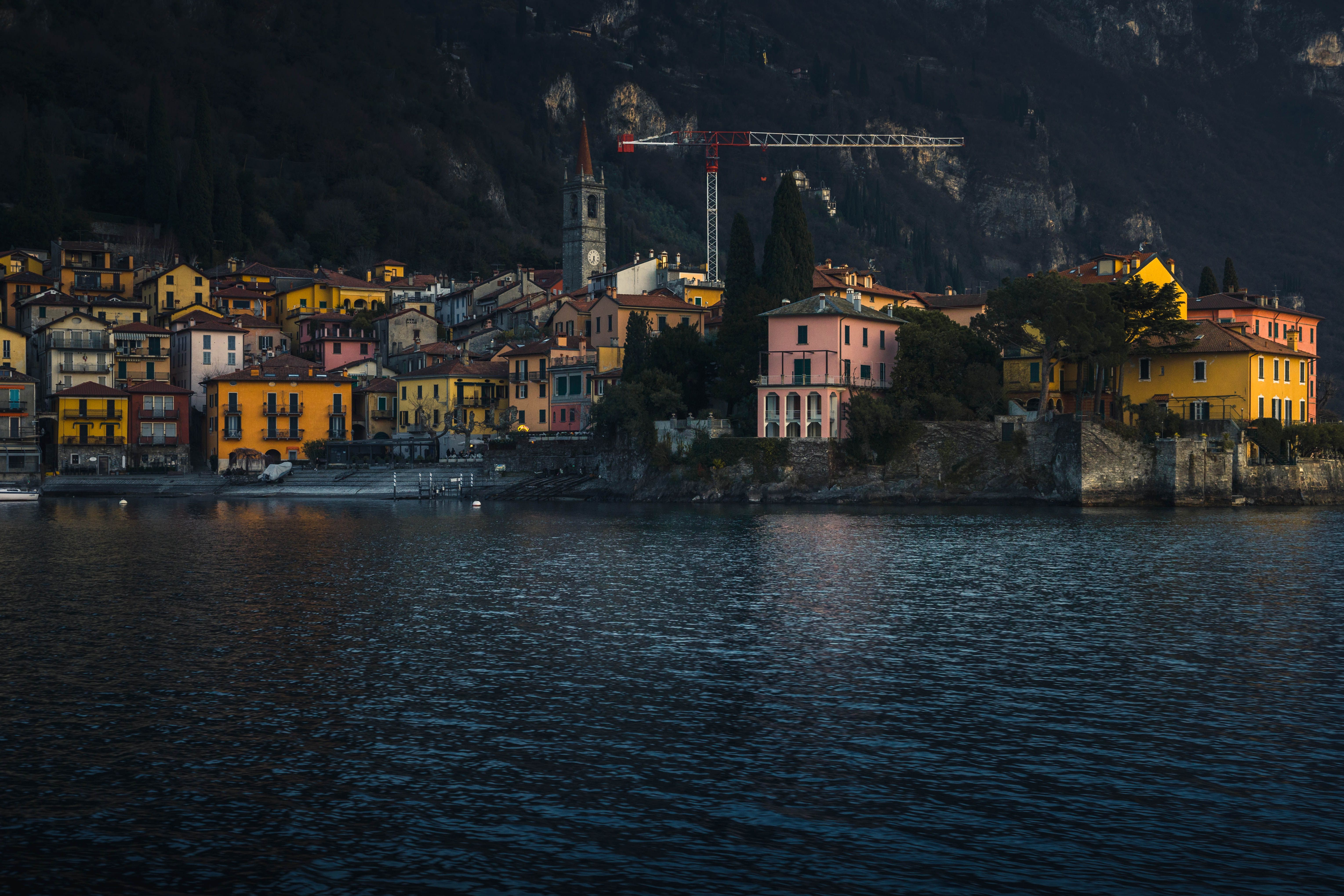A picturesque view of colorful village buildings by Lake Como, Italy, with serene waters. A picturesque view of colorful village buildings by Lake Como, Italy, with serene waters.