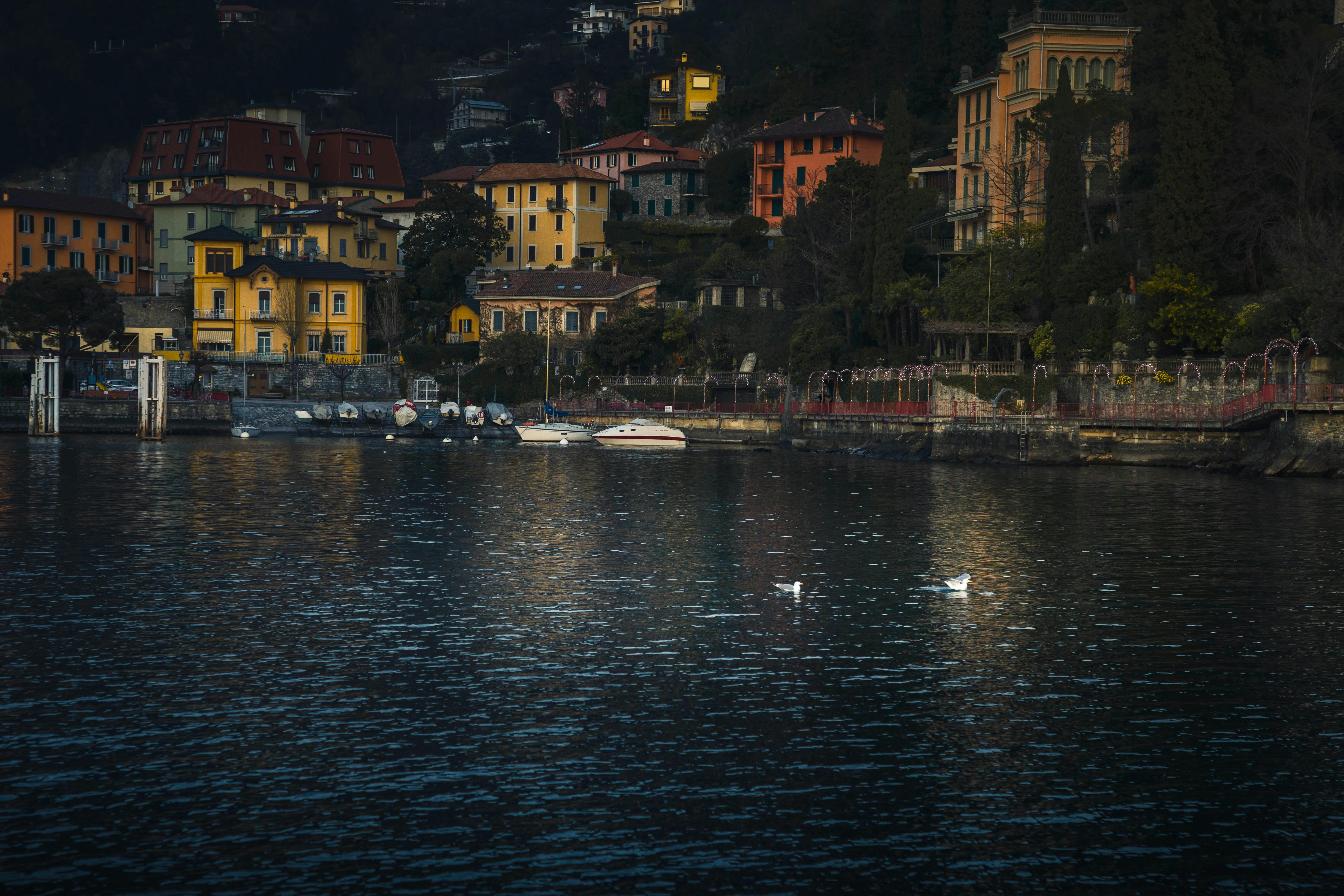 Charming view of colorful buildings and calm waters of Lake Como at dusk.