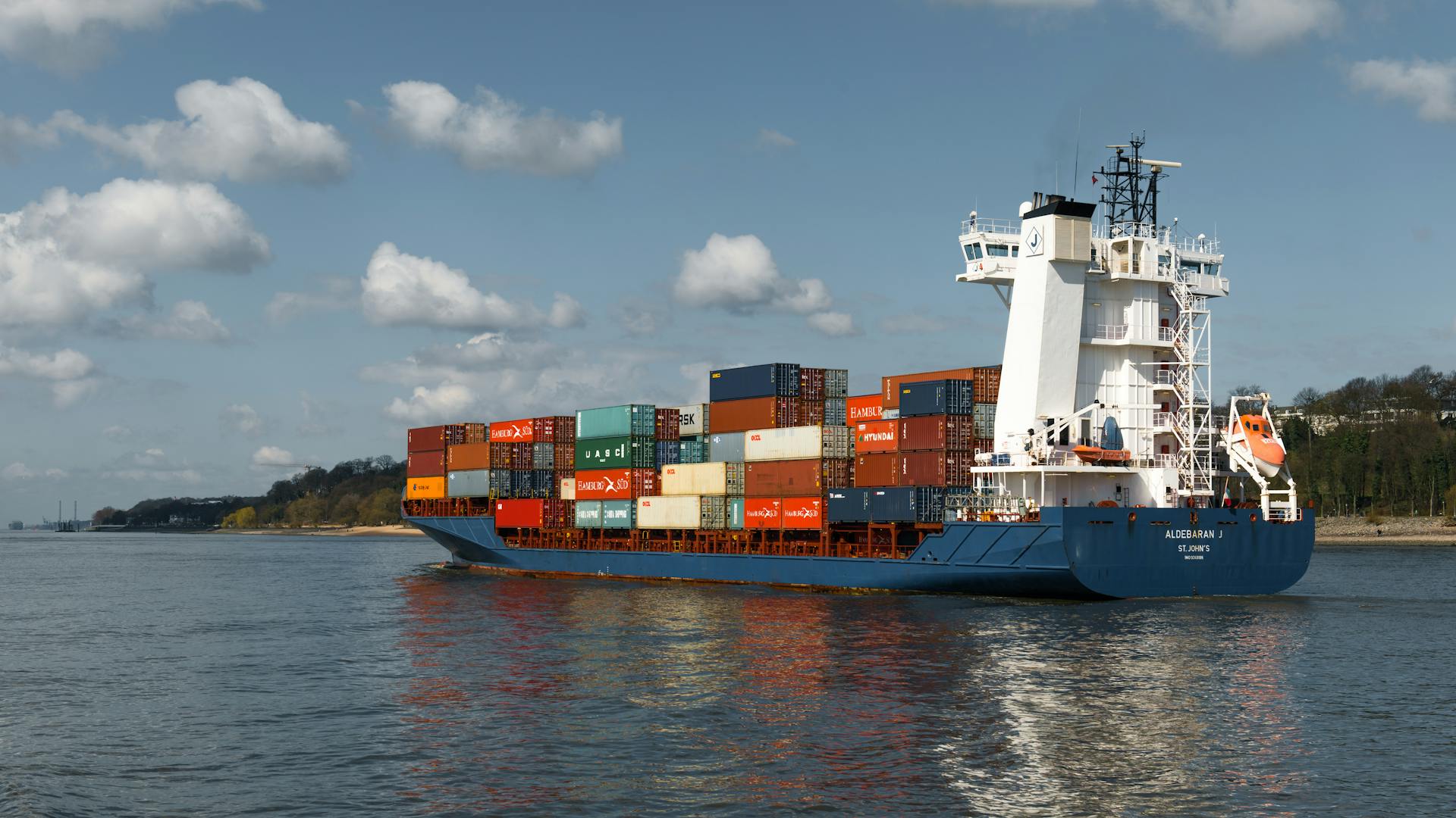 Container ship transporting goods on Elbe River, Hamburg on a clear day.