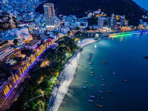 Free A stunning aerial view of a coastal city illuminated at night with colorful lights along the beach. Stock Photo