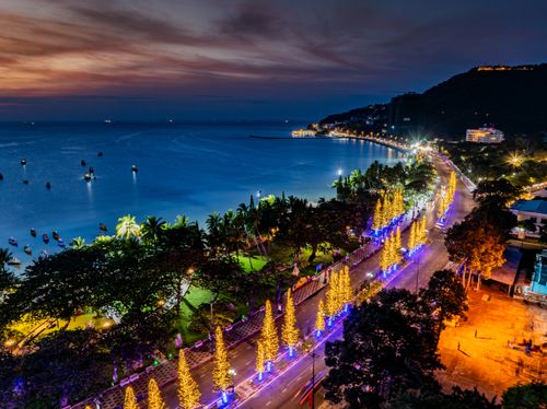 Free Aerial view of a seaside road lit up with festive lights at night, creating a vibrant and colorful scene. Stock Photo