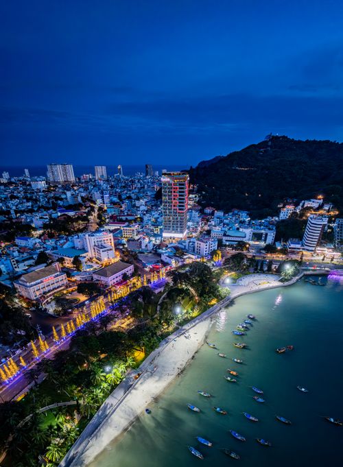 Free Vibrant aerial shot of a coastal city with illuminated skyline and beach at night. Stock Photo
