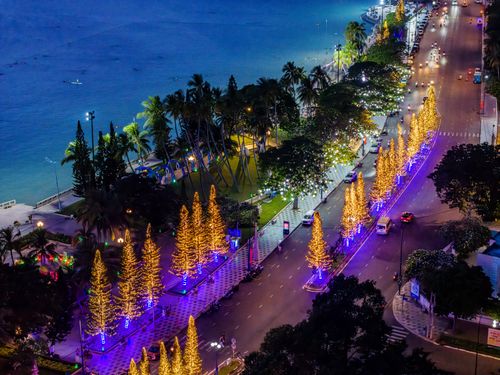 Free Beautiful coastal city street illuminated with holiday lights at night, creating a festive atmosphere. Stock Photo