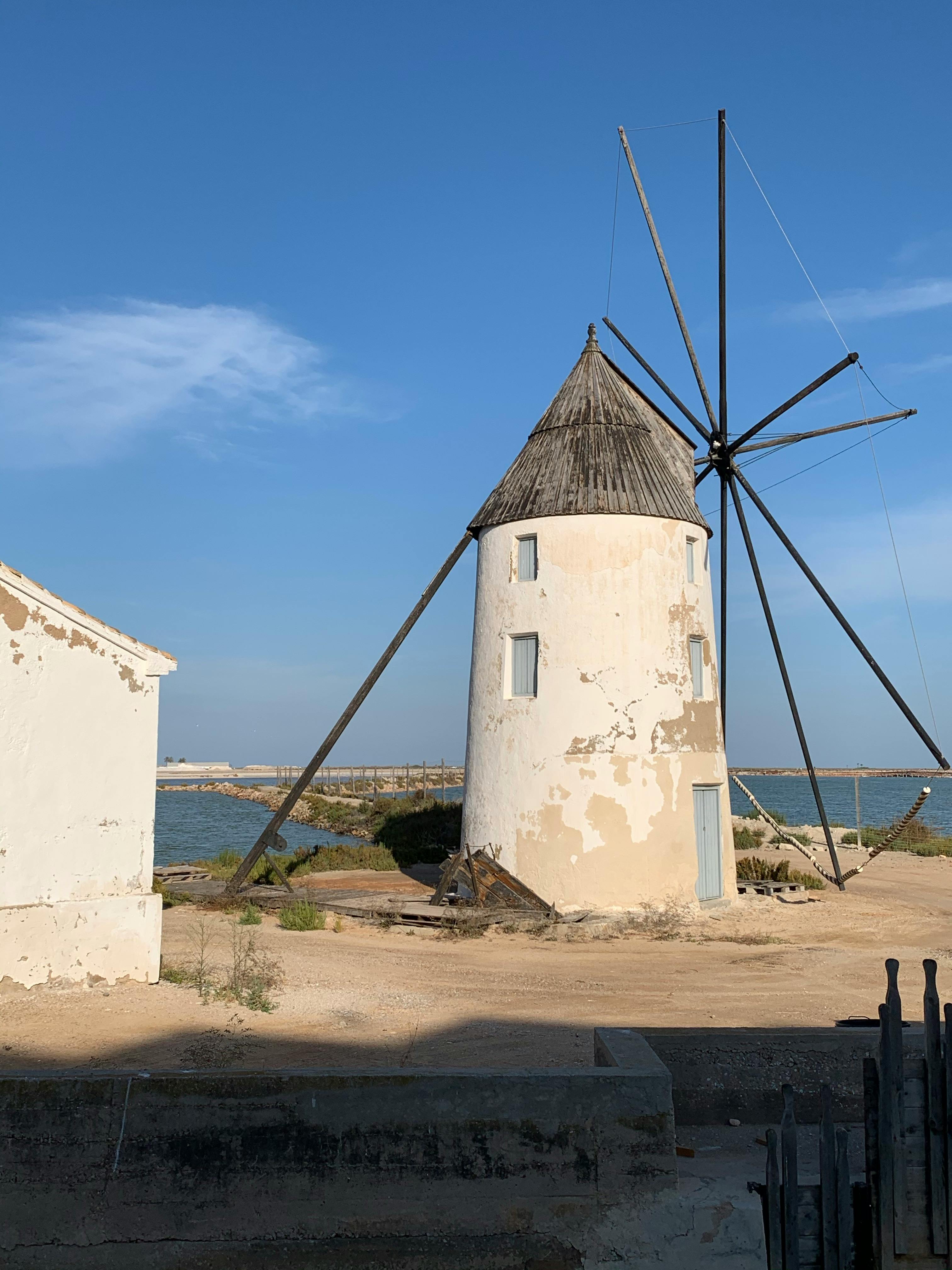Charming old windmill at the seashore with vivid blue sky and rustic surroundings.