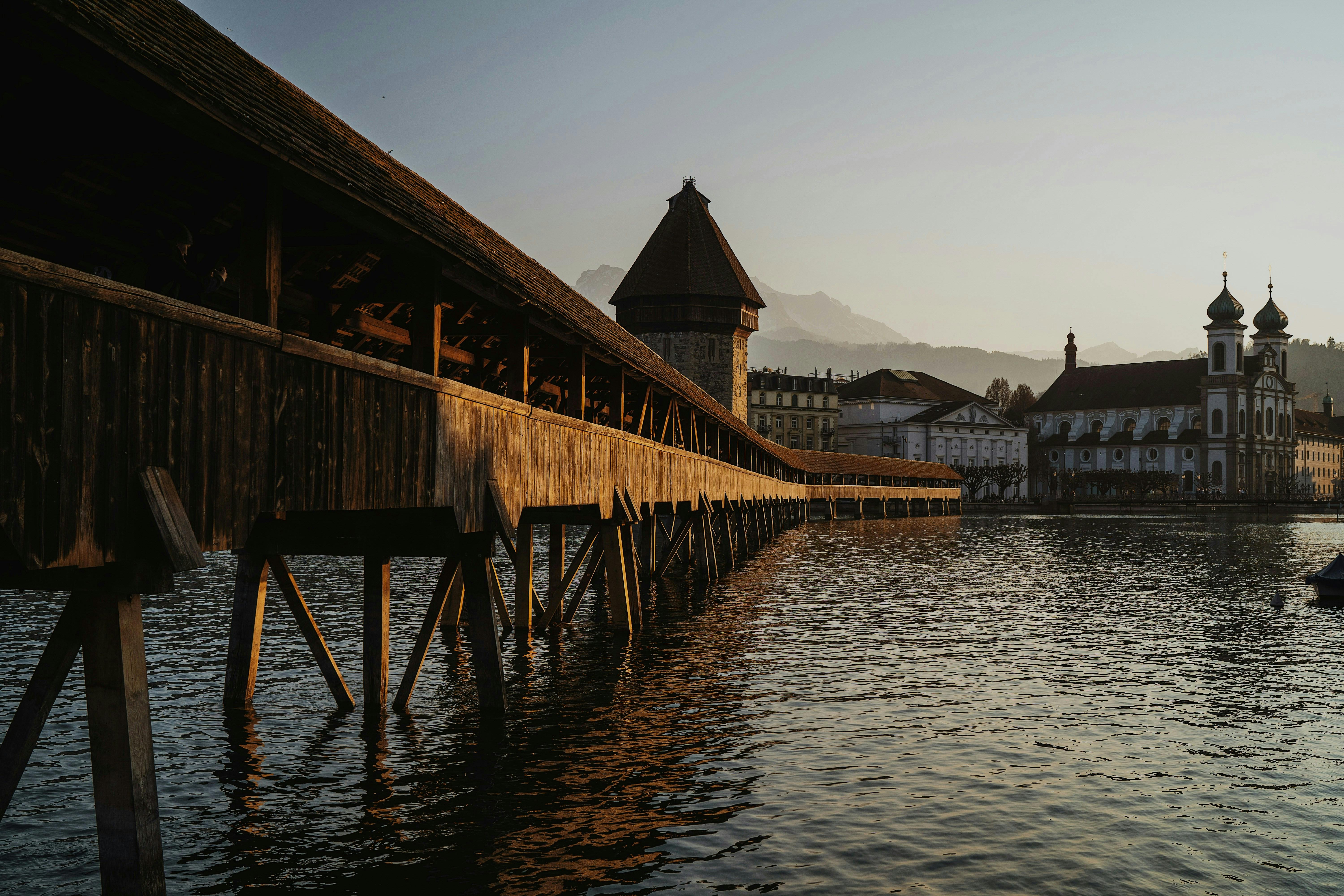Scenic view of Chapel Bridge and Water Tower during sunset in Lucerne, Switzerland.