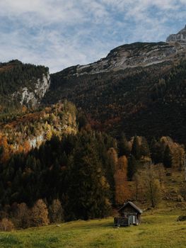 Beautiful autumn view of Swiss Alps with a rustic cabin nestled below.