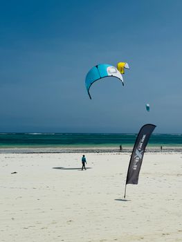 A serene beach setting featuring a kiteboarder under clear skies with vibrant kites.