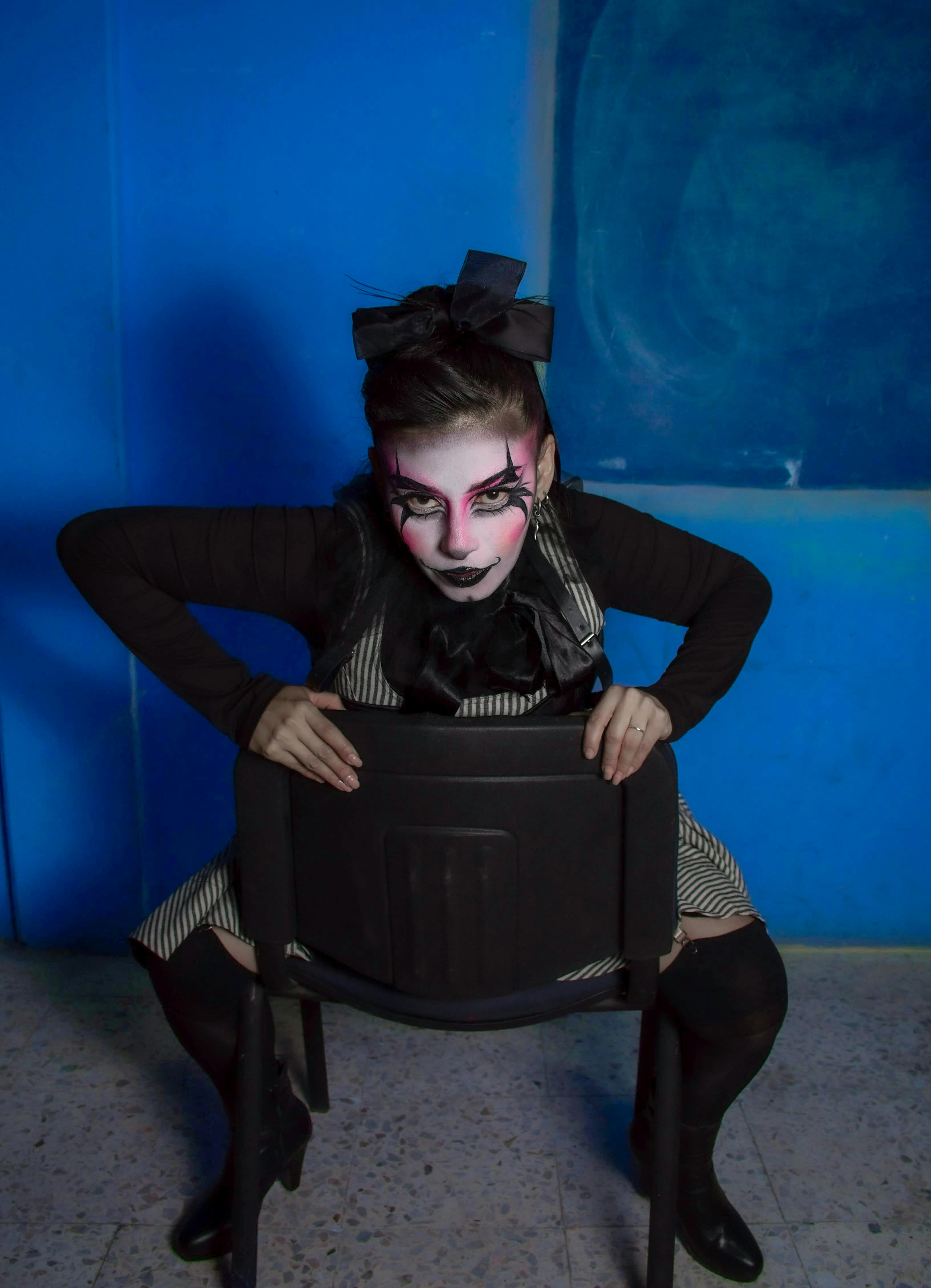 Kostenlos Beeindruckendes Porträt eines Darstellers mit Theater-Make-up, der vor einem blauen Hintergrund posiert. Stock-Foto