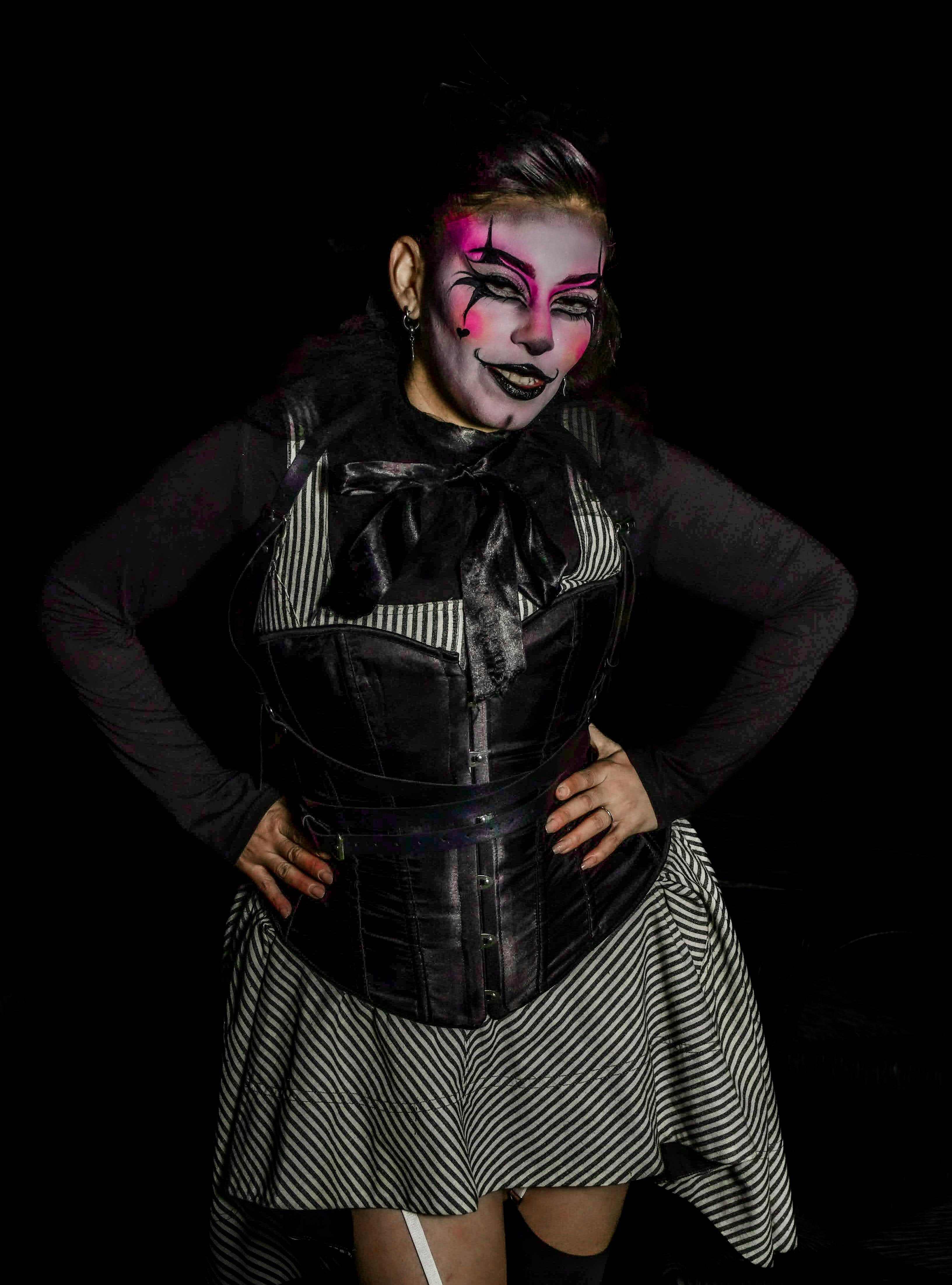 common:alt.prefix Femme au maquillage rose et noir dramatique avec une robe rayée capturée dans un éclairage vibrant. common:alt.postfix