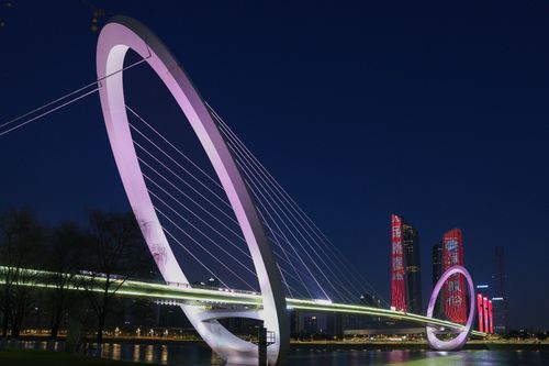 Free Stylish night shot of a modern bridge with illuminated arches reflecting on a river. Stock Photo