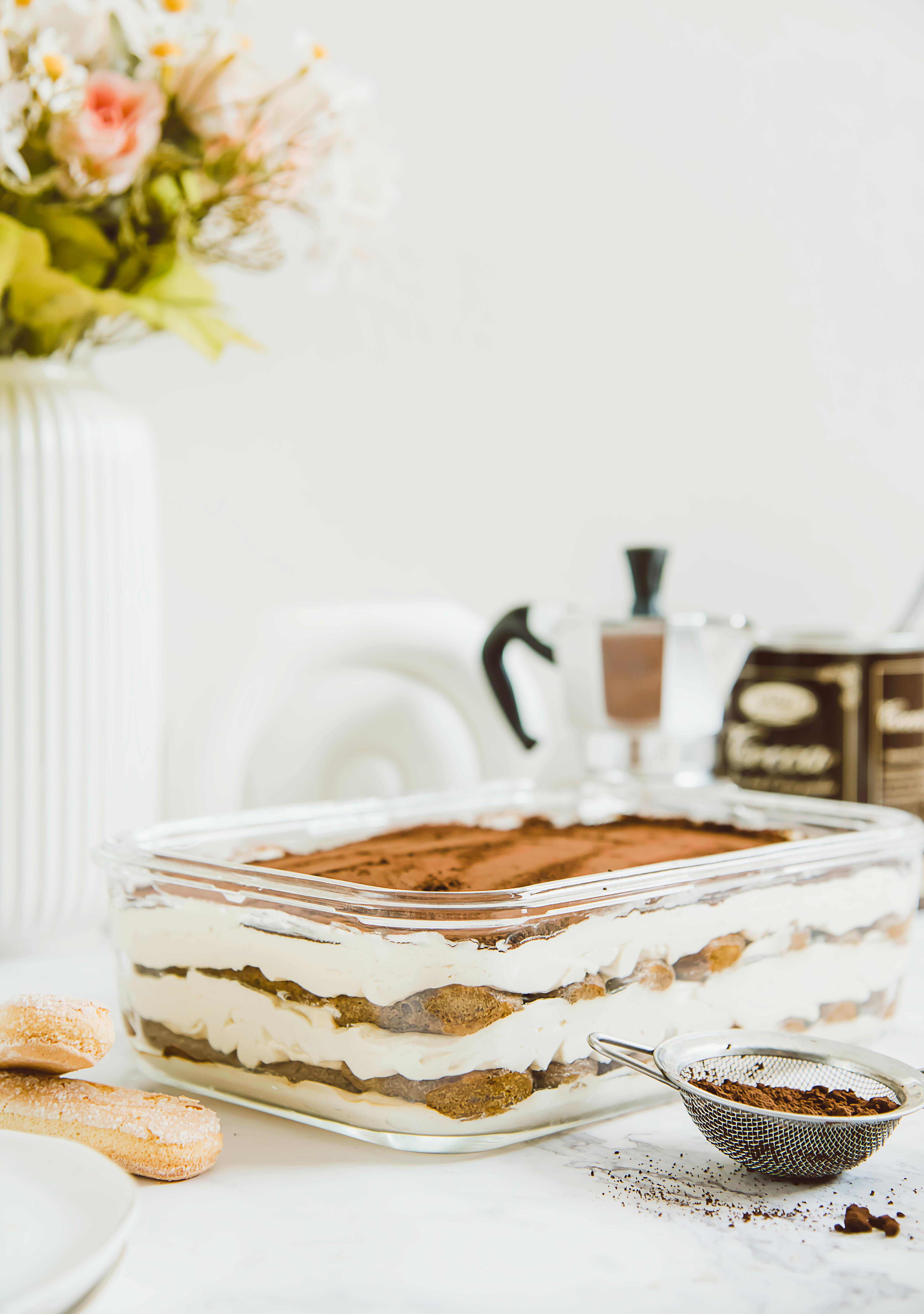 Beautiful layered tiramisu dessert with a coffee-focused setup, styled indoors in Riyadh.