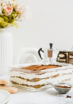 Beautiful layered tiramisu dessert with a coffee-focused setup, styled indoors in Riyadh.