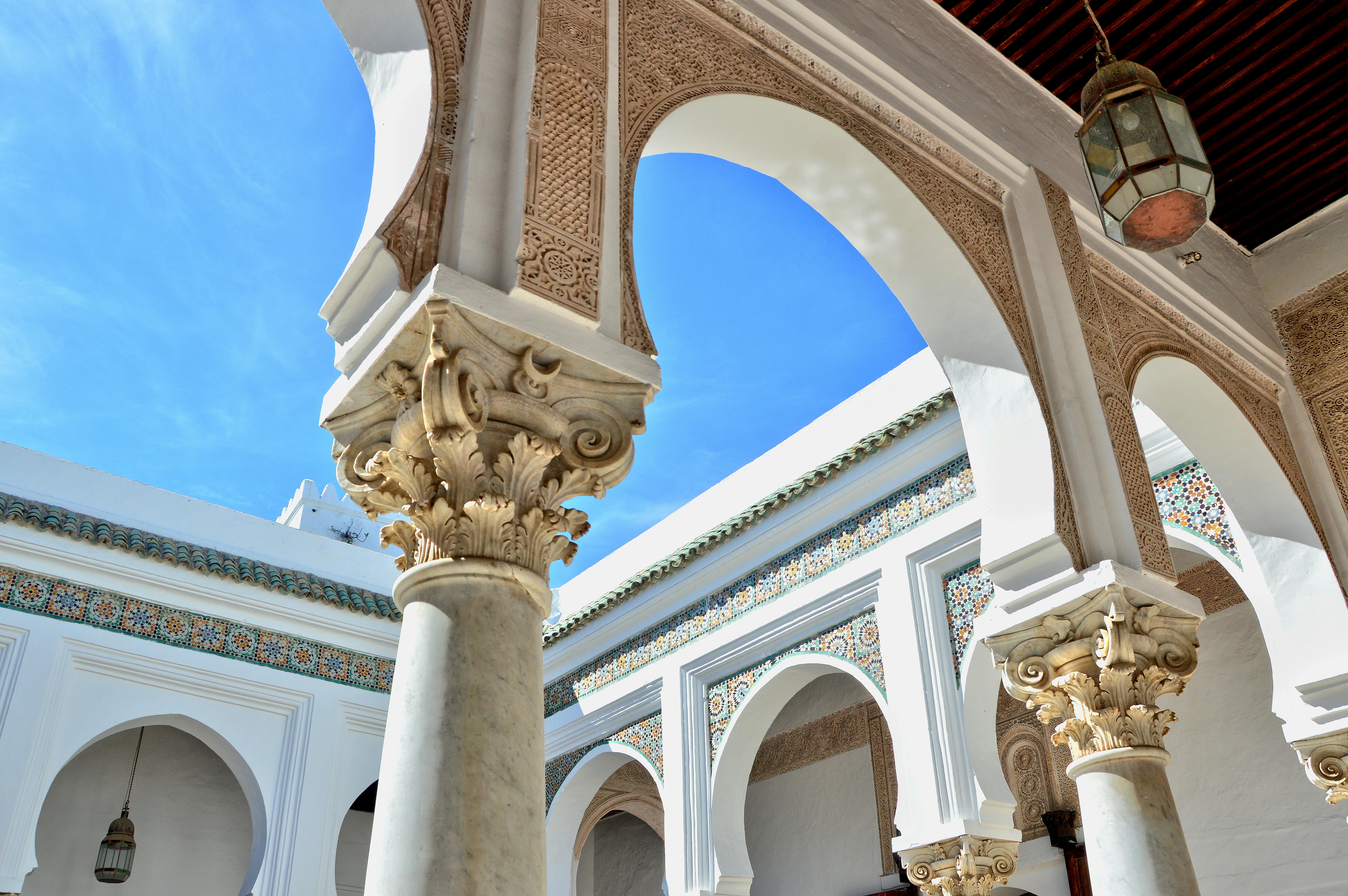 Intricate Moroccan courtyard with arches and columns under a bright blue sky in Tanger, Morocco.