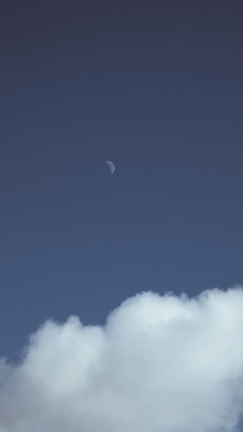 Free A serene view of the half moon with white clouds against a blue sky, evoking calmness and tranquility. Stock Photo