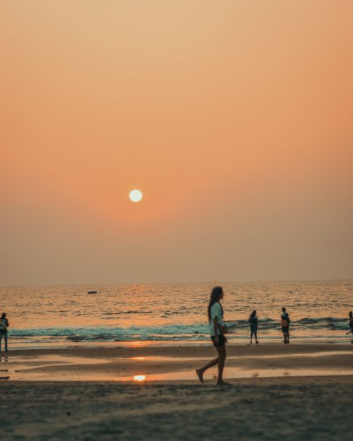 Free People enjoying a calm evening stroll along the beach at sunset. Stock Photo