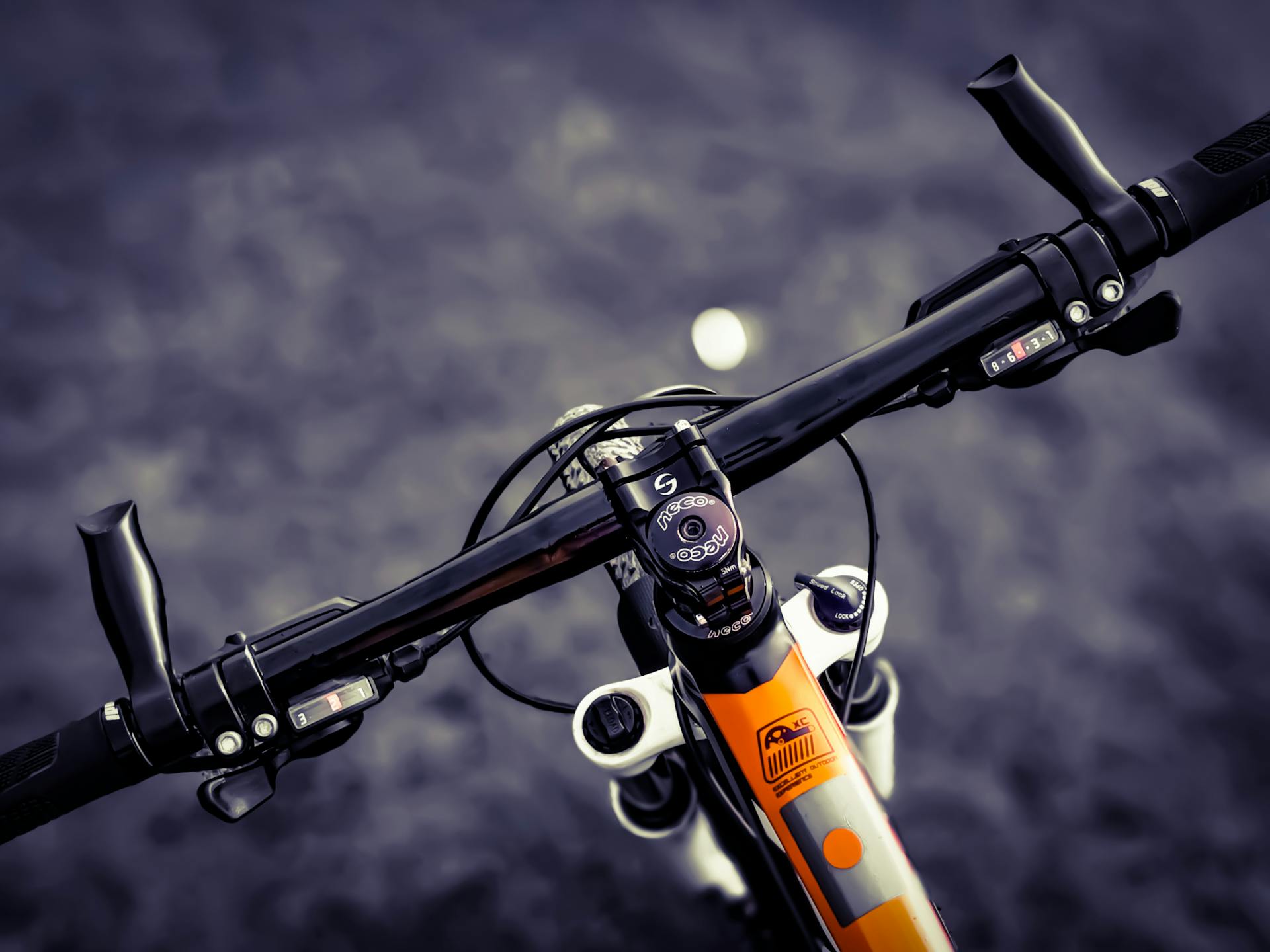 Close-up of a mountain bike handlebar with visible gear shifters and detailed components.